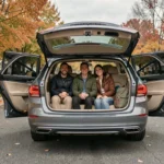 Famille installée confortablement sur les trois places arrière d'une berline familiale spacieuse, portes ouvertes sur une rue résidentielle en automne